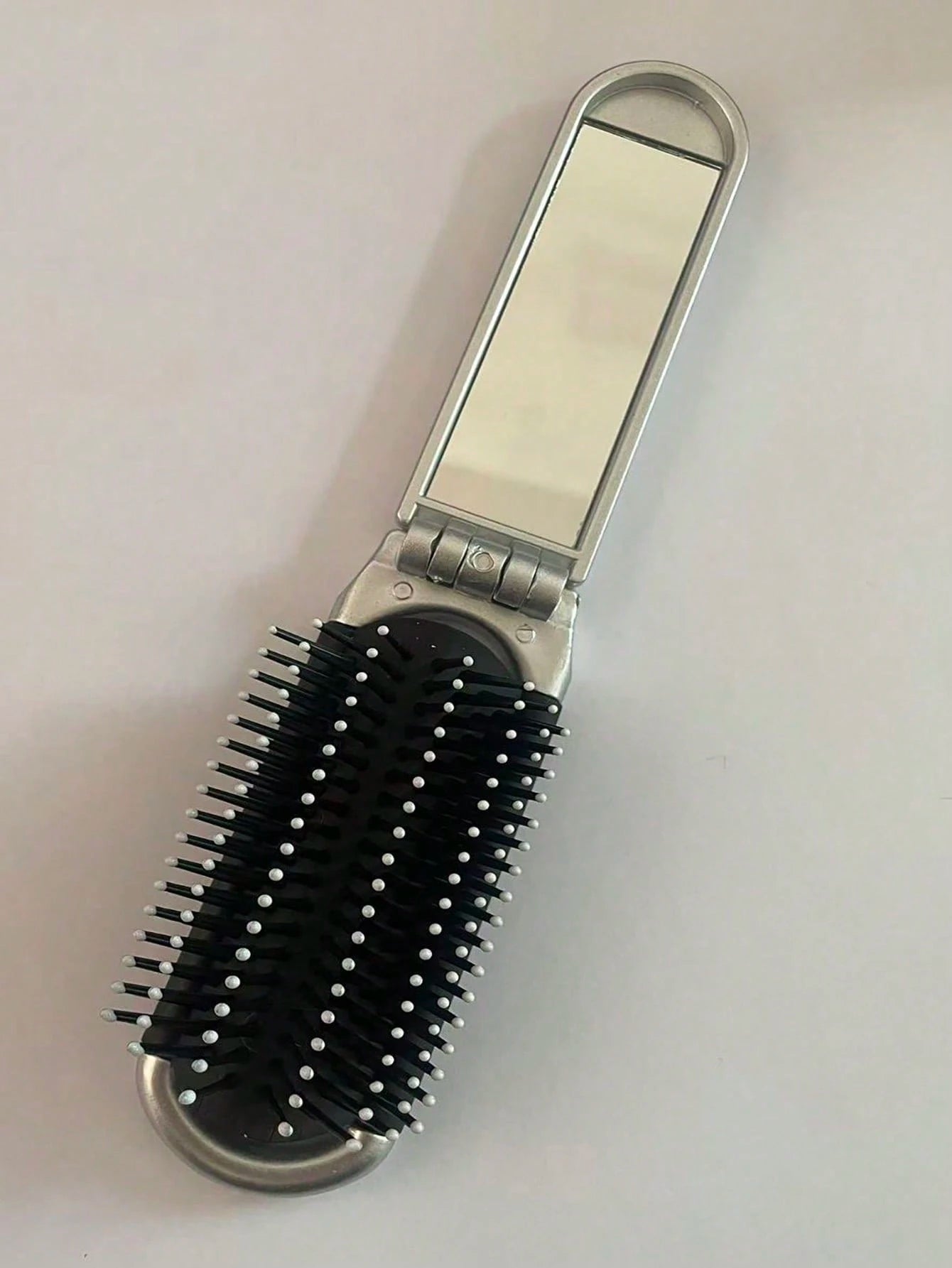 A Shiny Electroplated Silver Comb With A Foldable Design, A Small Mirror, Compact And Portable